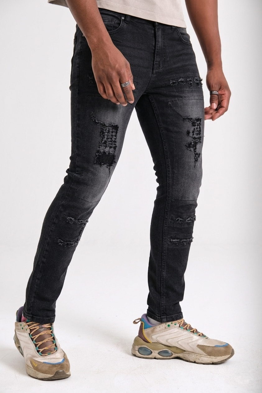 Distressed black denim rip-repair detail — Clutch Denim